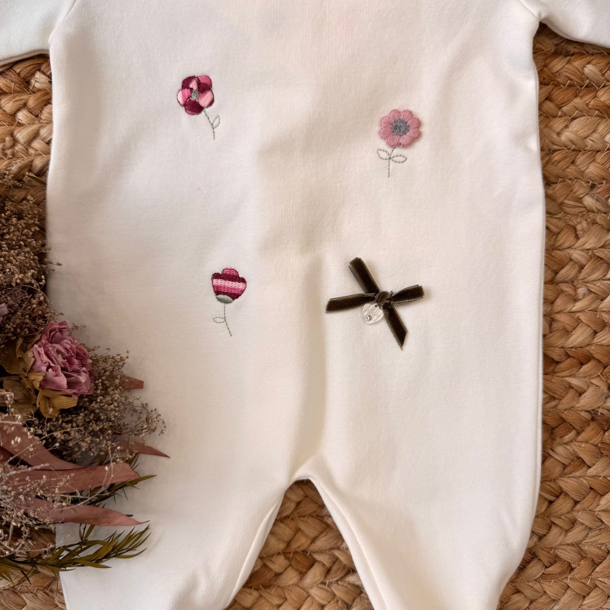 Ricami a fiorellini rosa e rossi con fiocco in velluto e charm applicato.