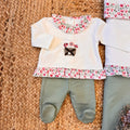 Tutina due pezzi per neonata con colletto e fondo floreale, pantalone verde foglia.