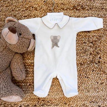 Tutina in ciniglia panna per neonato con orsetto centrale e colletto beige.