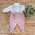 Tutina in ciniglia rosa cipria con colletto e bretelle floreali per neonata.