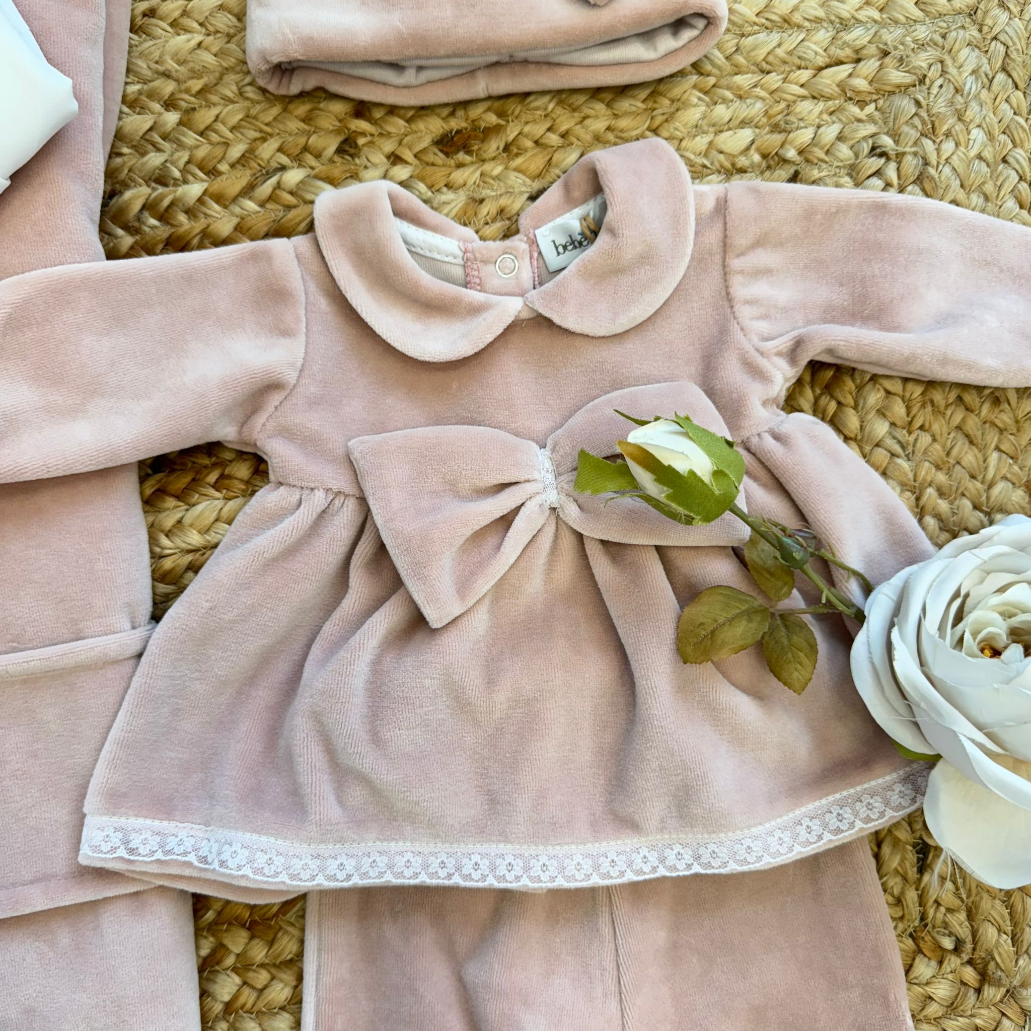 Tutina neonata in ciniglia rosa con fiocco centrale e bordo in pizzo