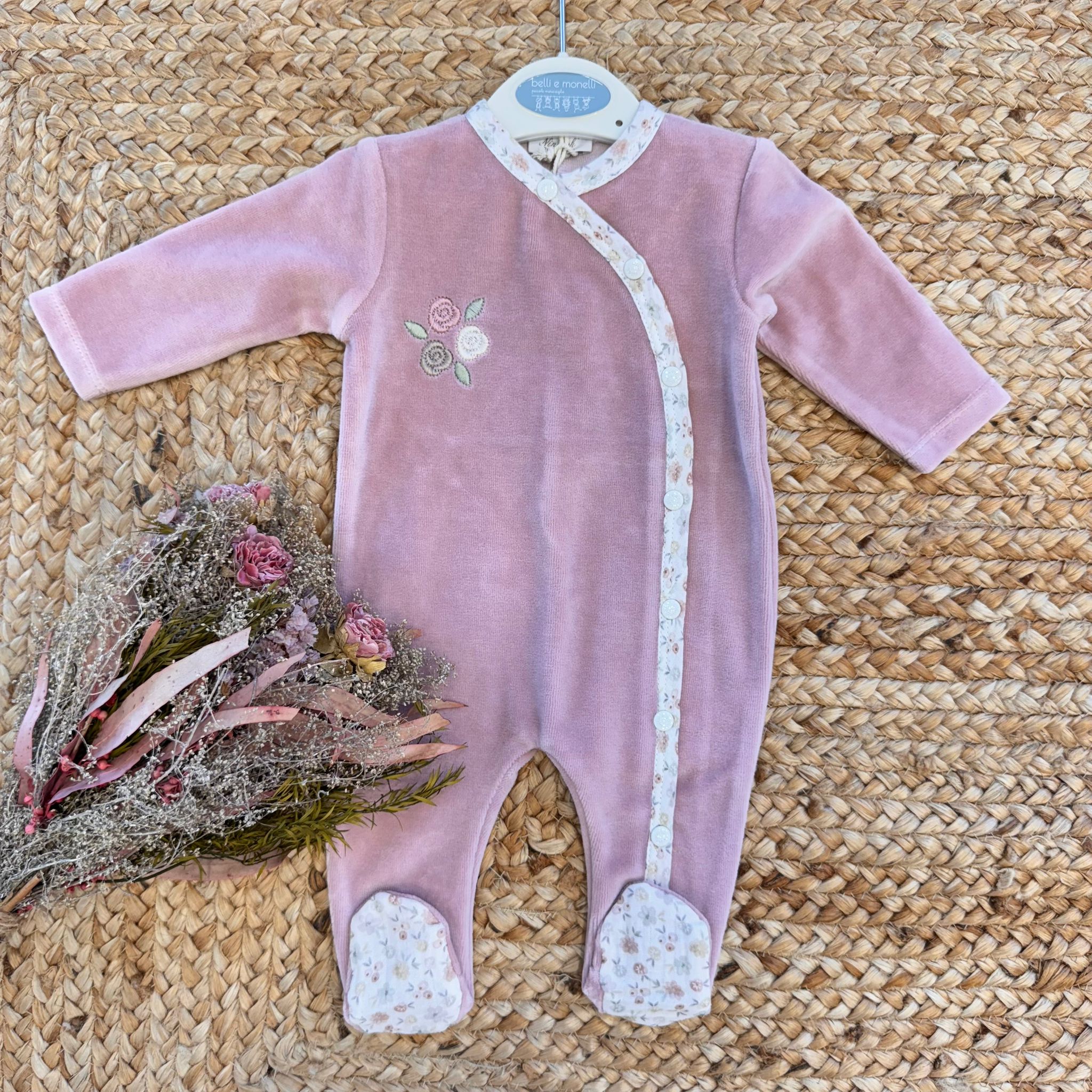 Tutina neonata in ciniglia rosa con ricami floreali e dettagli fantasia.