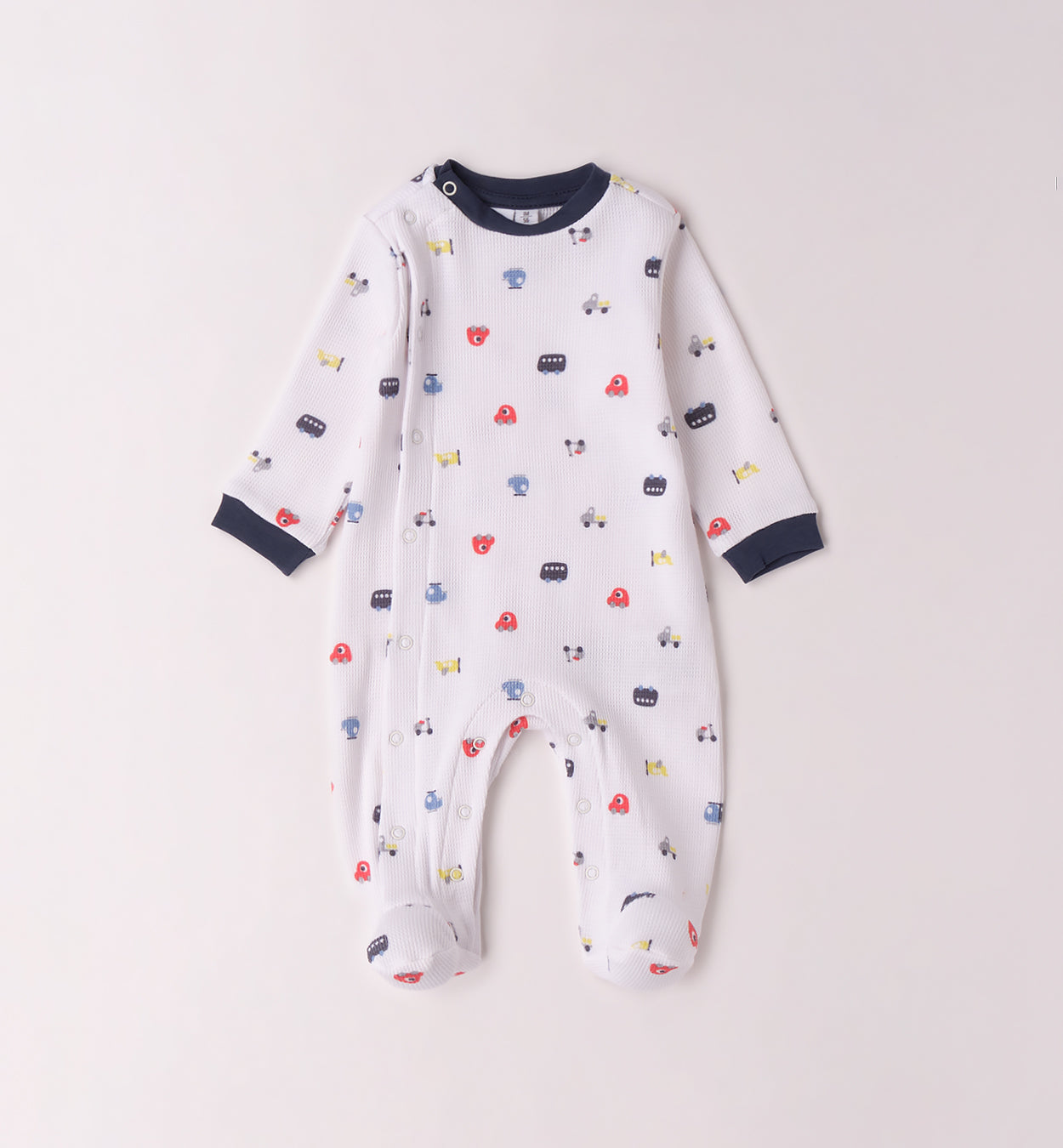 Tutina per neonato in cotone bianco con stampa macchinine colorate, colletto a contrasto e chiusura con bottoni a pressione, perfetta per la nascita.

