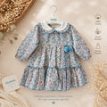 Abitino bimba floreale 100% cotone con colletto bianco e pon pon azzurri.