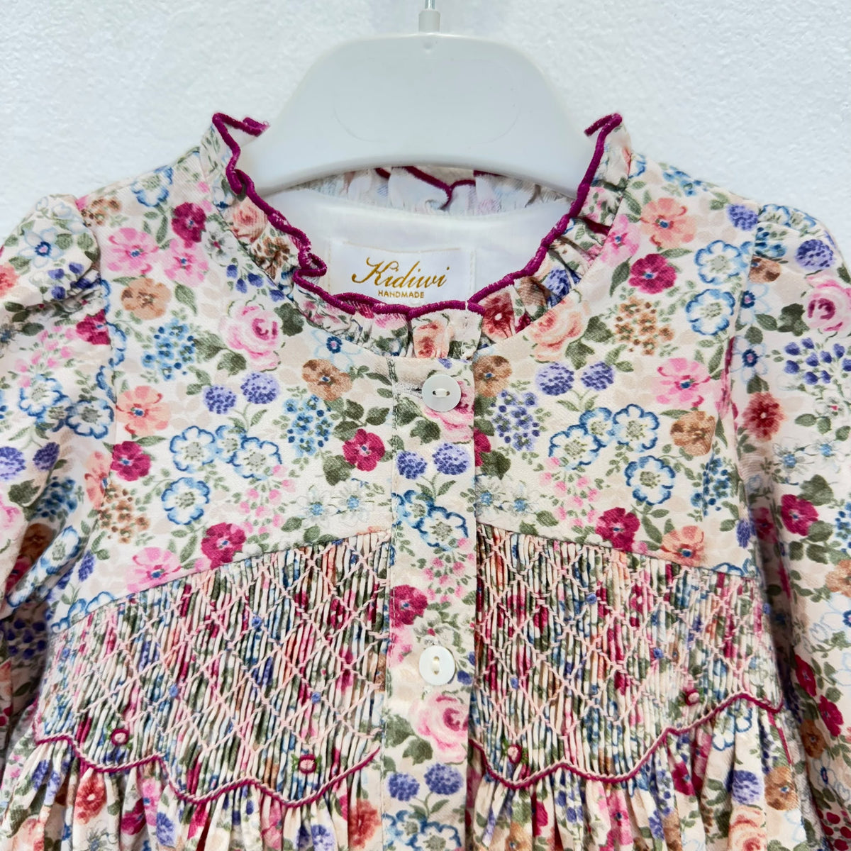 Abito bambina floreale in cotone con punto smock, colletto arricciato e dettagli bordeaux Kidivi.