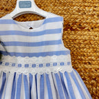 Dettaglio pizzo bianco ricamato su abito a righe per bambina
