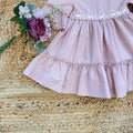 Vestito bambina elegante rosa cipria con pizzo in vita e balze morbide.