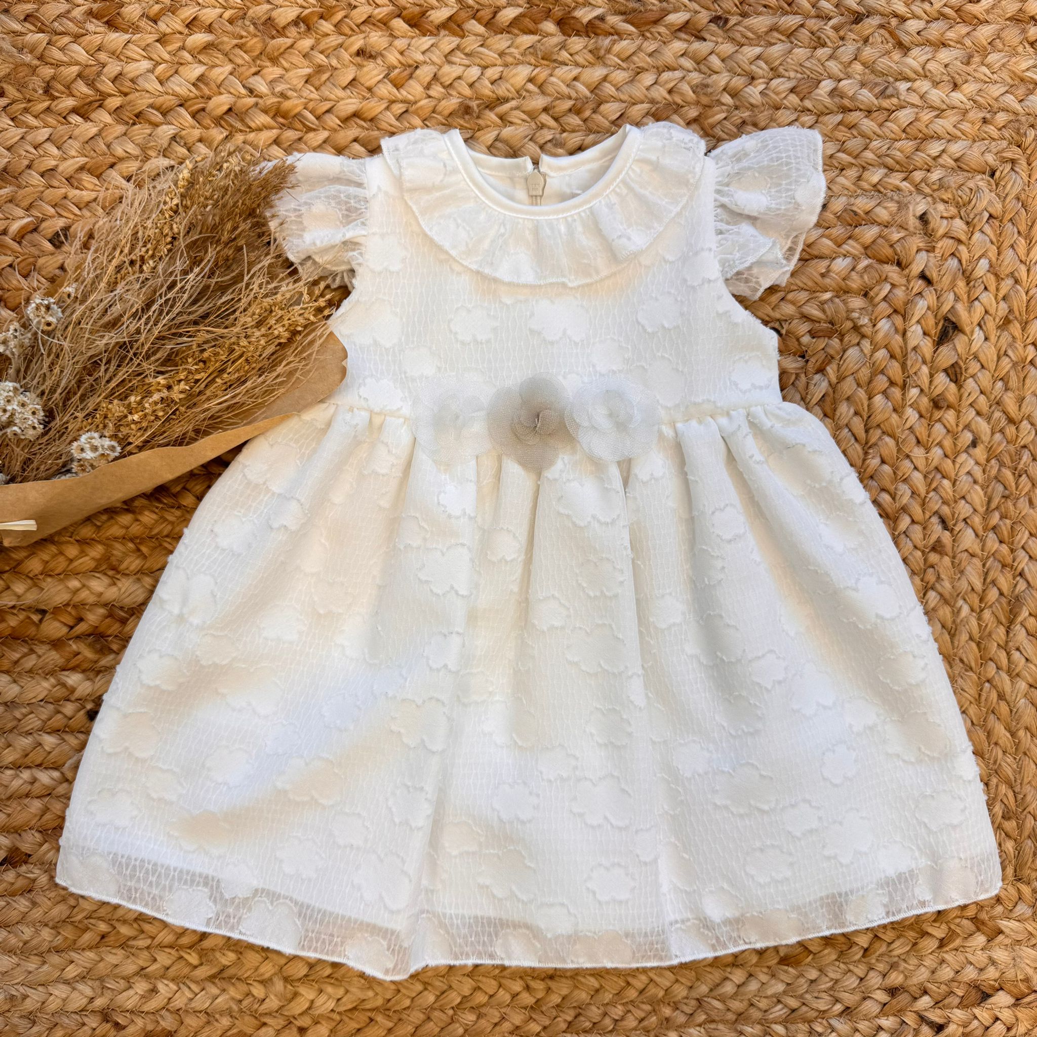 Abito da battesimo bambina con colletto, maniche a sbuffo e decorazioni floreali.