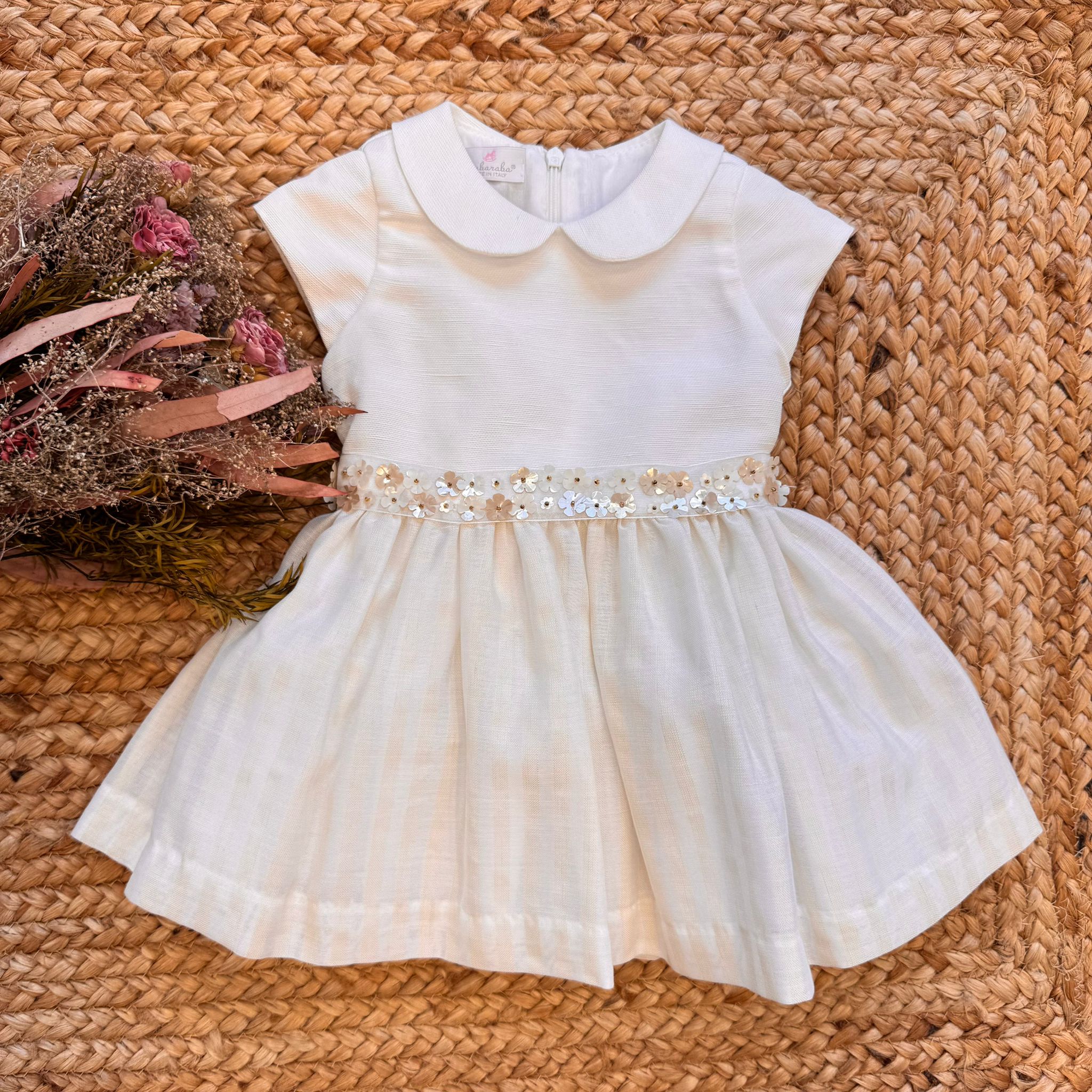 Abito battesimo bambina panna con fiori applicati e fiocco posteriore.