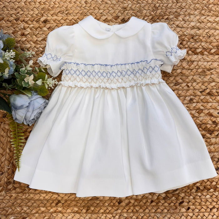 Abito battesimo bambina in shantung bianco con smock celeste, maniche a palloncino e colletto tondo.