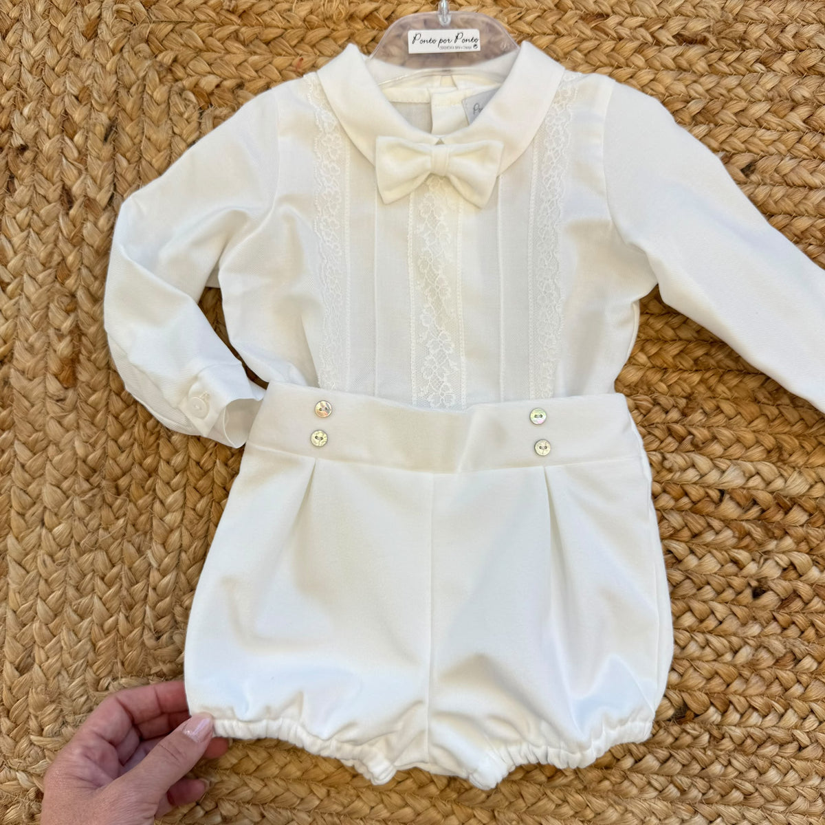 Completo battesimo neonato bianco con camicia a maniche lunghe decorata in pizzo floreale, papillon e pantaloncino a palloncino.