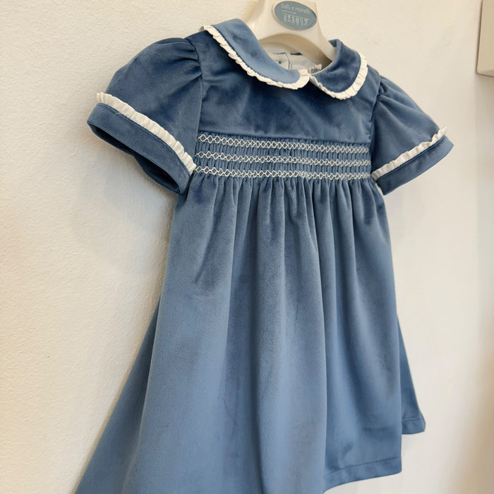 Dettaglio dell'abito bambina in velluto azzurro polvere con lavorazione smock, ricami panna e maniche corte con volant.