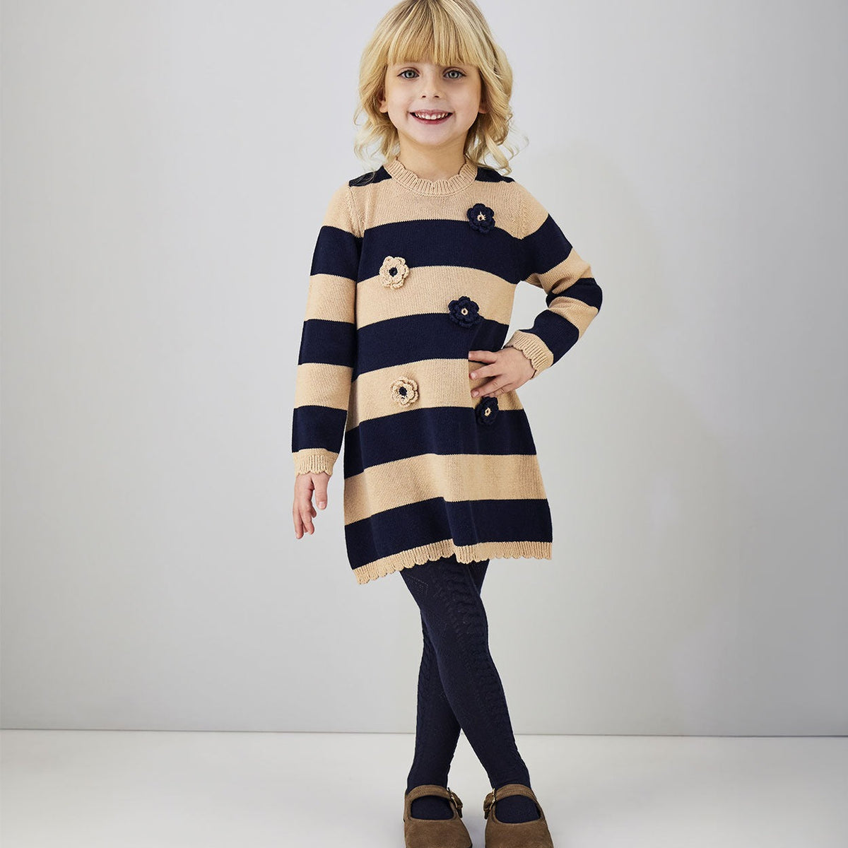 Abito bimba blu e beige in maglia a righe con fiori applicati indossato