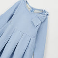 Abito bimba celeste lurex con fiocco sulla spalla, maniche lunghe e gonna a pieghe