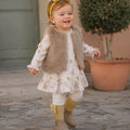 Bimba con abito panna a fantasia floreale e gilet morbido beige