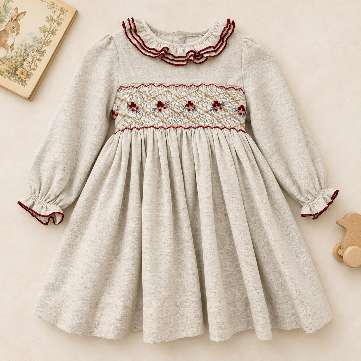 Abito bimba grigio chiaro in cotone con punto smock, ricami floreali e colletto a volant bordeaux.