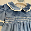 Dettaglio dell'abito bambina in velluto azzurro polvere con lavorazione smock, ricami panna e maniche corte con volant.