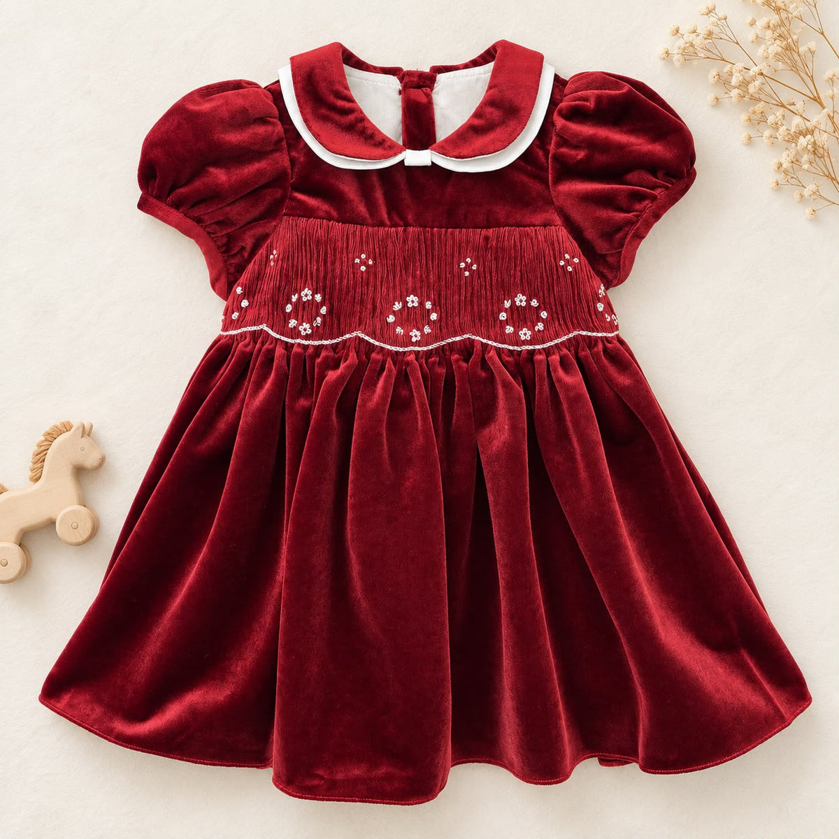 Abito bimba in velluto bordeaux con punto smock, colletto bianco a contrasto e maniche a palloncino.