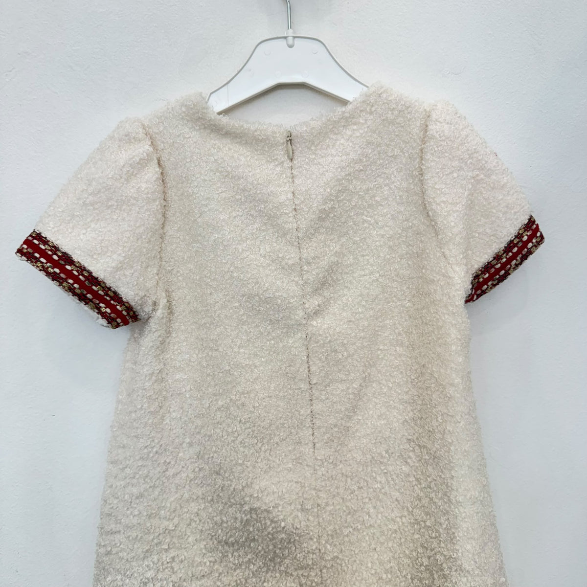Dettaglio abito elegante bambina panna bouclé con passamaneria bordeaux e decorazioni di perline