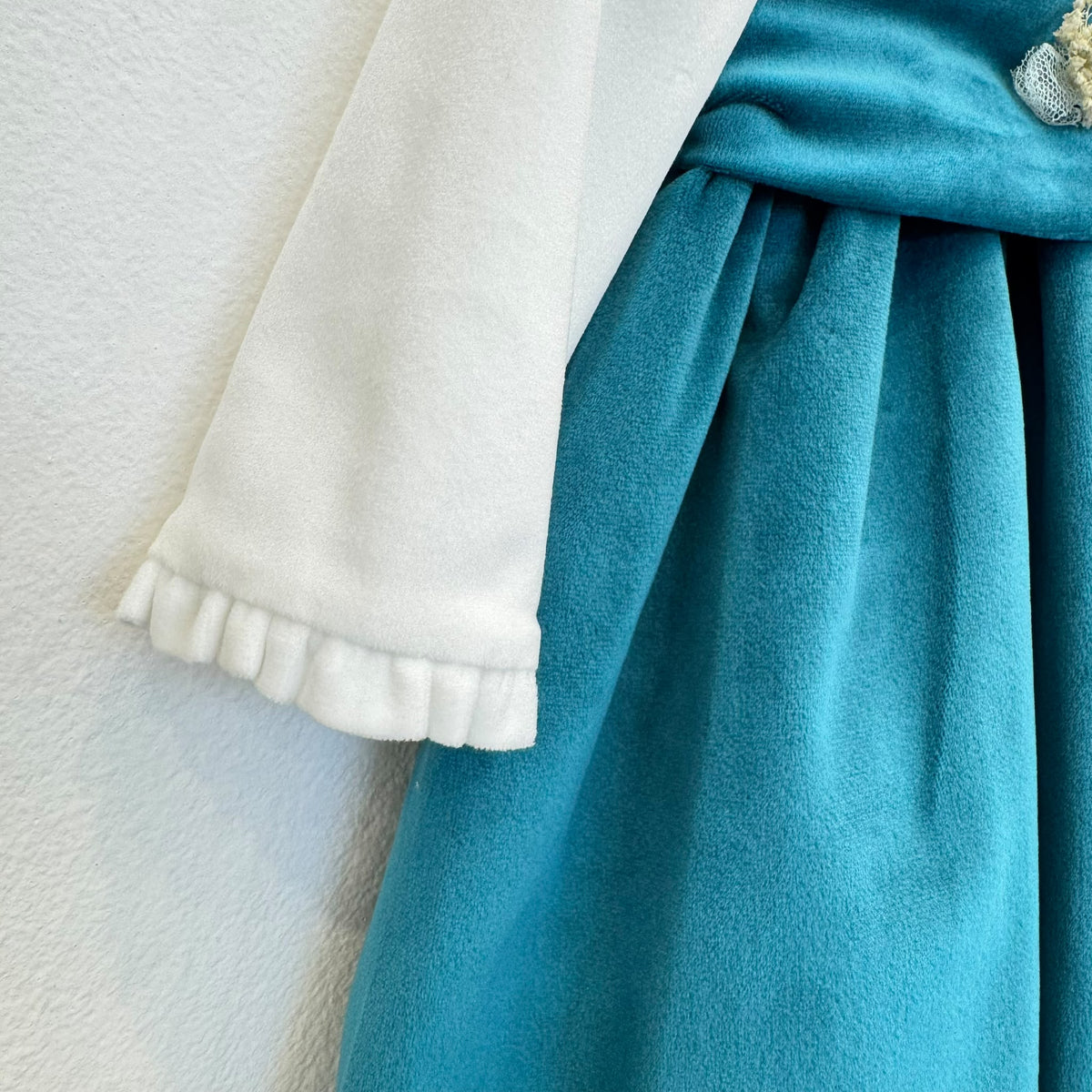 Dettaglio abito elegante bimba in velluto ottanio con corpetto panna e fiori rosa