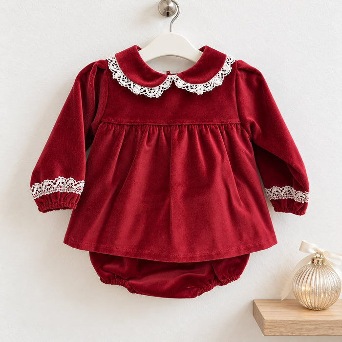 Abito neonata in velluto rosso con culotte coordinata, colletto Peter Pan rifinito in pizzo bianco, maniche lunghe e gonna arricciata.