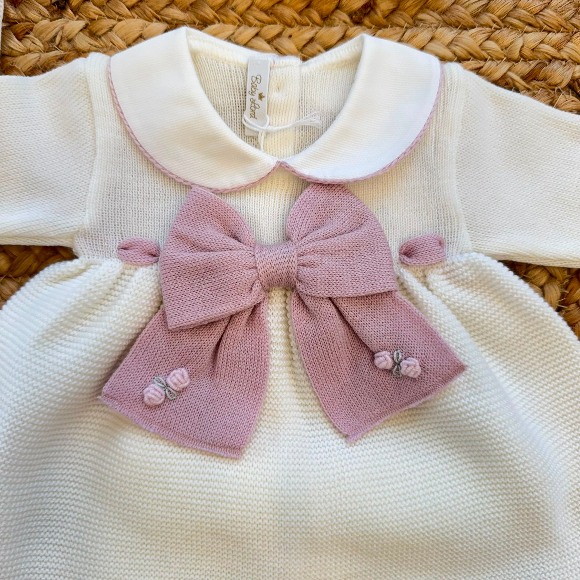 Uscita clinica neonata in pura lana bianca con fiocco rosa e copertina coordinata.