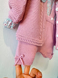 Completo bimba rosa antico con cardigan a trecce, salopette in maglia e maglia floreale con colletto volant