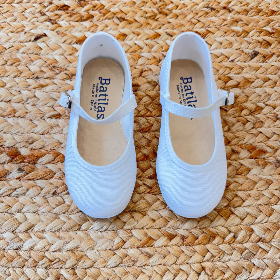 Ballerine bianche in tessuto per bambina con cinturino e fibbia laterale, ideali per cerimonie e occasioni speciali.