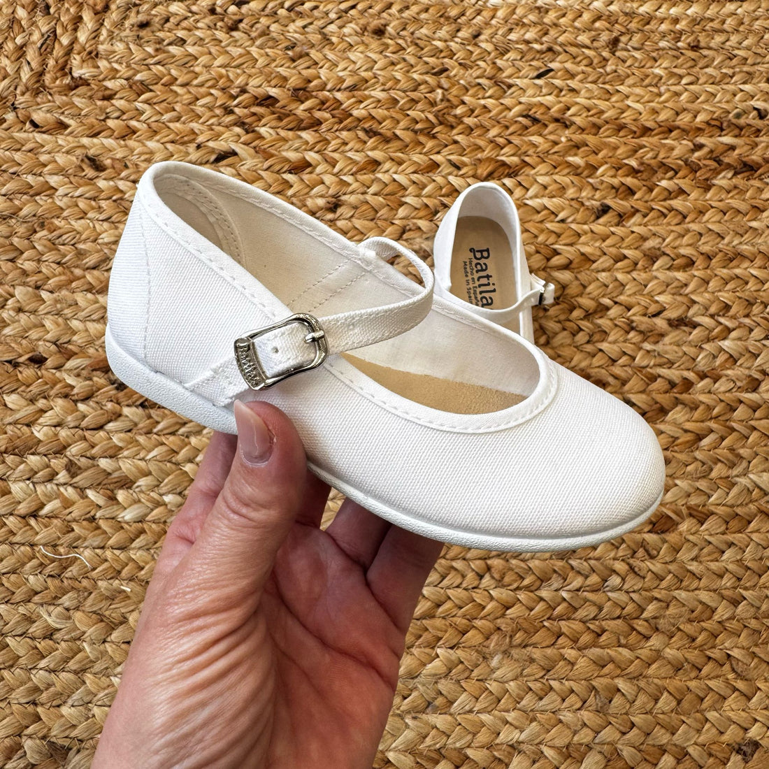 Ballerine bianche in tessuto per bambina con cinturino e fibbia laterale, ideali per cerimonie e occasioni speciali.