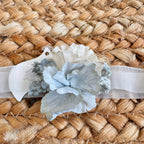 Fascetta battesimo bambina con fiori azzurri su nastro elastico bianco