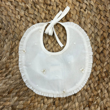 Bavaglino bianco con volant e farfalle ricamate color panna per neonata.