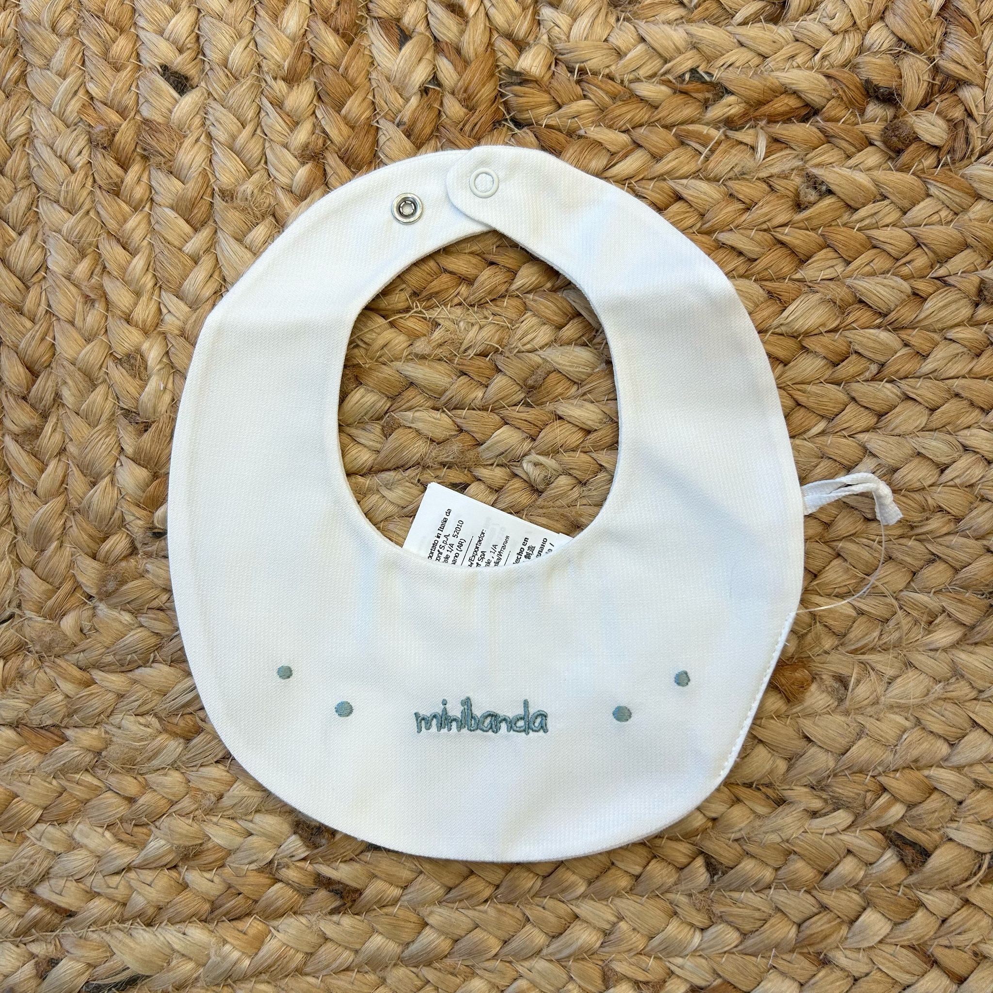 Bavaglino neonato bianco con pois ricamati verde salvia e chiusura a clip.