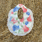 Bavaglino neonata in cotone con fiori e farfalle acquerello, balza arricciata e strass decorativi a forma di B.

