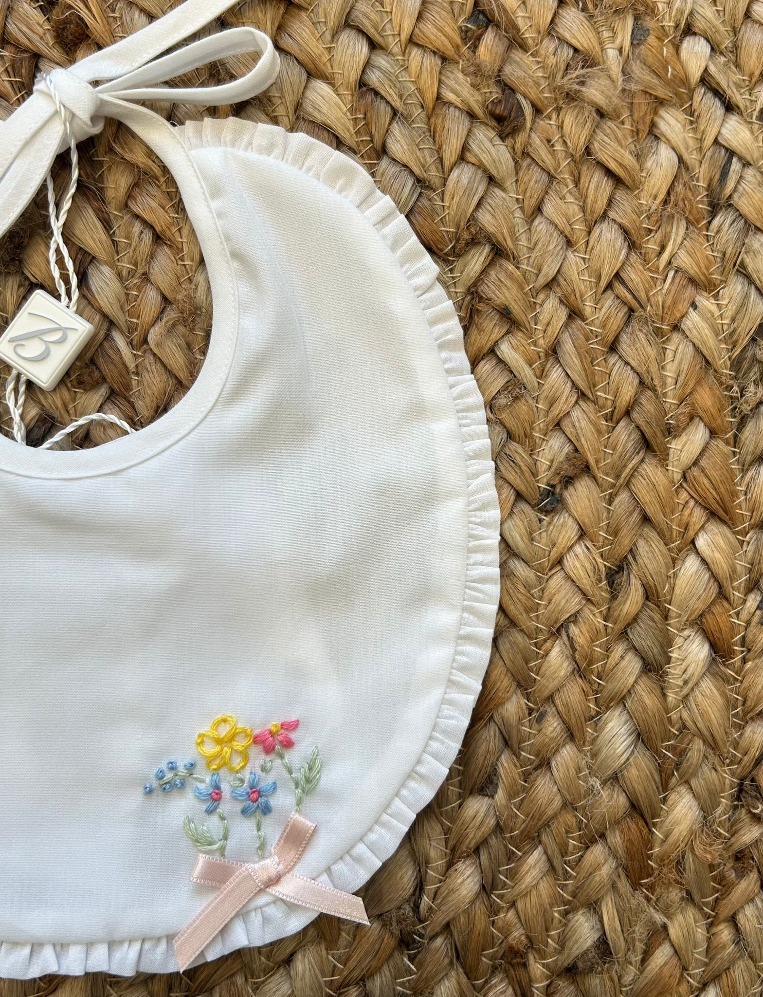 Bavaglino bianco con ricami floreali e fiocco rosa cipria