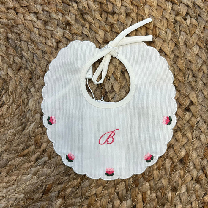 Bavaglino bianco con bordo smerlato e roselline ricamate nei toni del rosa.