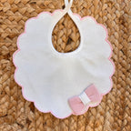 Bavetta bianca neonata con profilo rosa smerlato e fiocco applicato in maglia – accessorio corredino autunno inverno