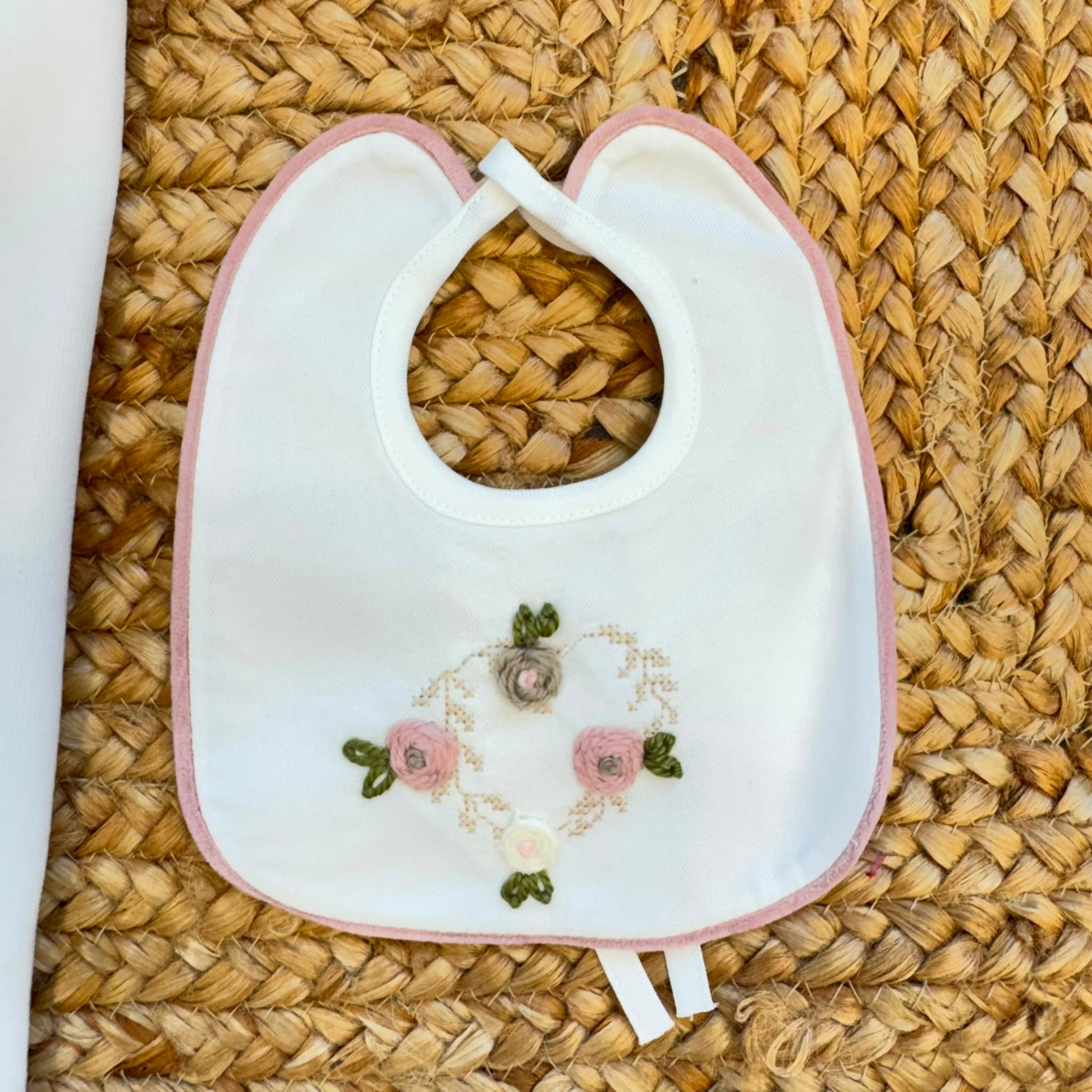 Uscita clinica neonata in ciniglia bianca e rosa con completino ricamato a cuore floreale, fiocco applicato, cappello, bavetta, scarpine, lenzuola coordinate e copertina sfoderabile.