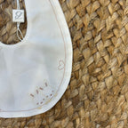 Bavaglino elegante per neonata con ricamo coniglietti, cuore e scritta "my cutie" in cotone panna.

