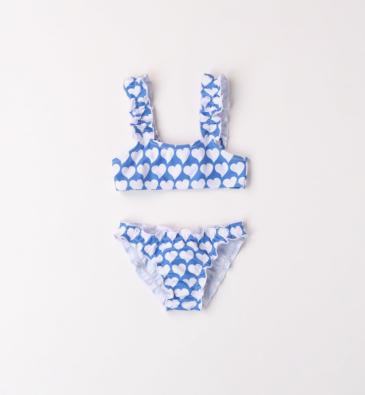 Bikini bambina azzurro con cuori bianchi, top con spalline a volant e slip con balza.


