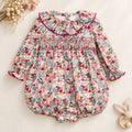 Pagliaccetto bimba floreale in cotone con punto smock e colletto a volant fucsia.