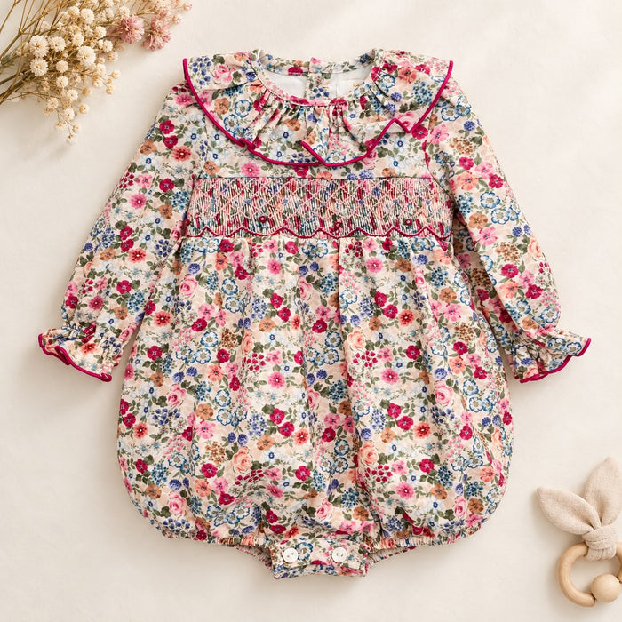 Pagliaccetto bimba floreale in cotone con punto smock e colletto a volant fucsia.