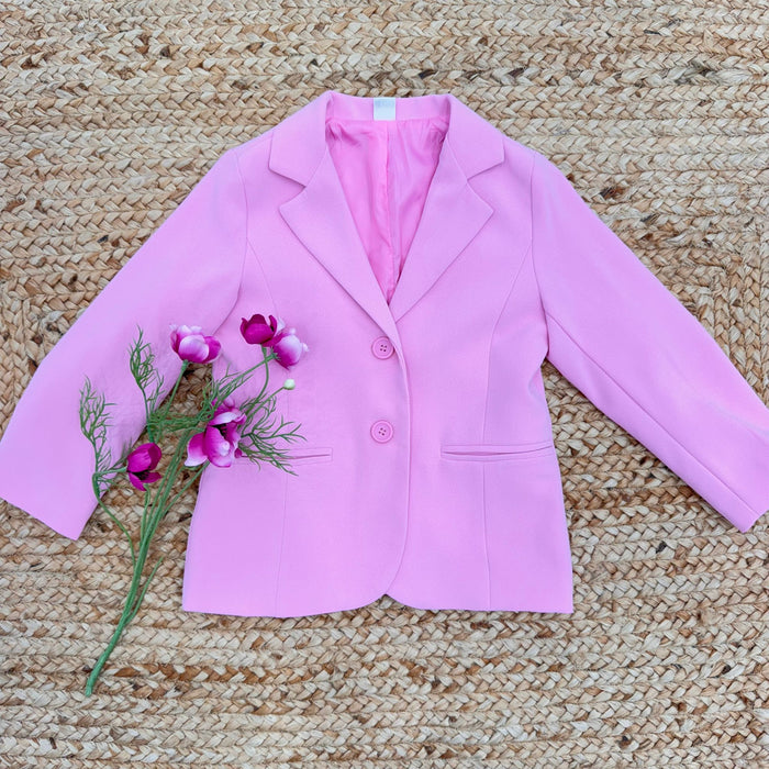 Blazer bambina rosa confetto con bottoni tono su tono e fiori decorativi.