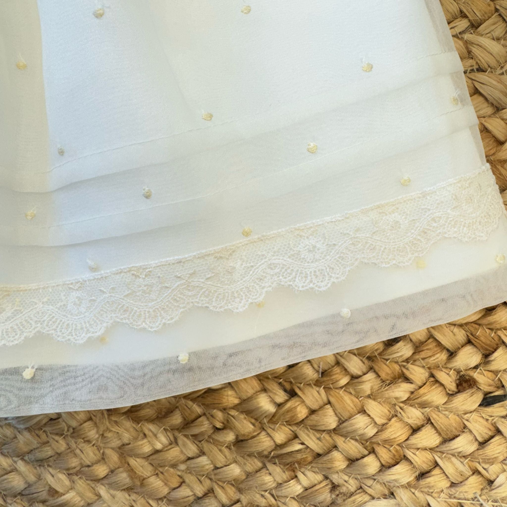 Orlo con pizzo ricamato e pois su abito cerimonia neonata