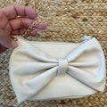 Borsa a tracolla bimba beige con grande fiocco frontale e catena dorata.