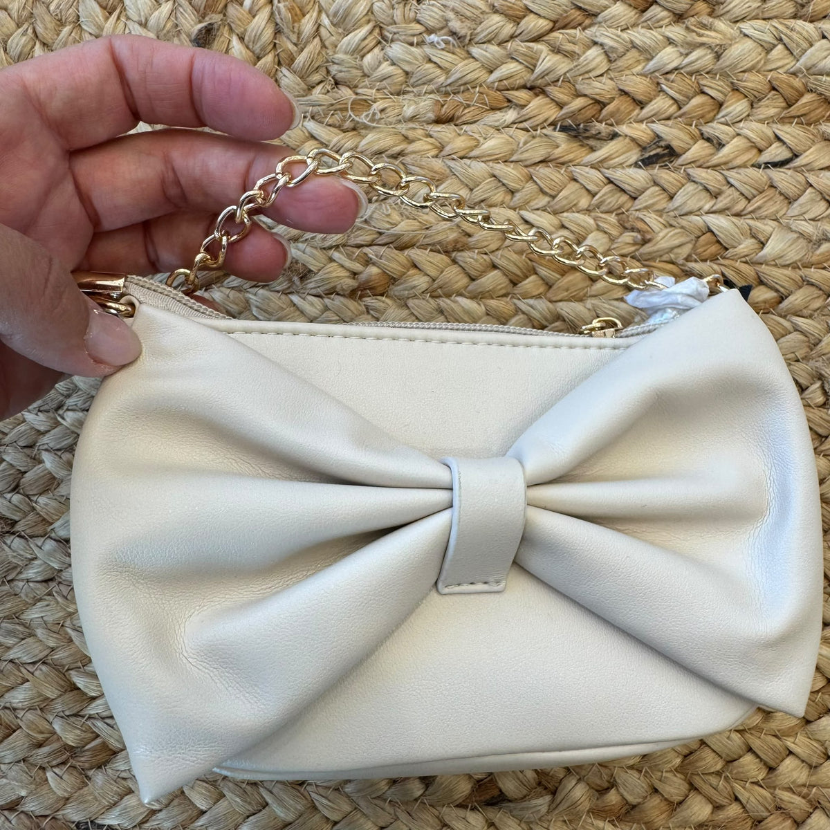 Borsa a tracolla bimba beige con grande fiocco frontale e catena dorata.