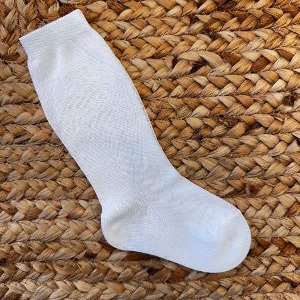Calze lunghe bianche in cotone per battesimo bimbo su sfondo naturale