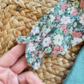 Completo bimba con salopette in maglia verde petrolio e camicia floreale a maniche lunghe