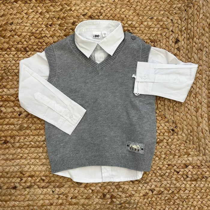camicia bimbo bianca con gilet grigio appoggiati su tappeto