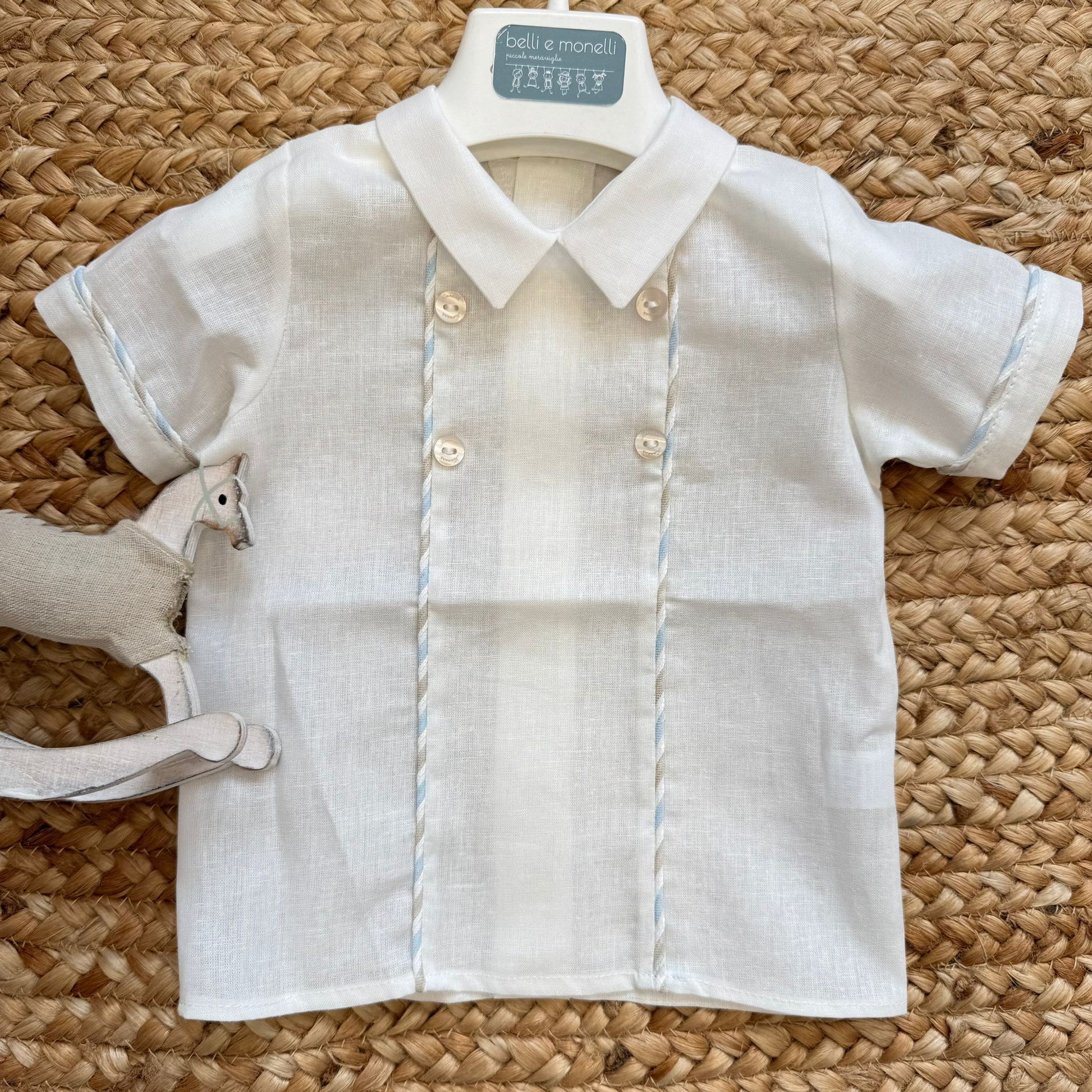 Dettaglio camicina bianca con profili celesti e bottoni raffinati.