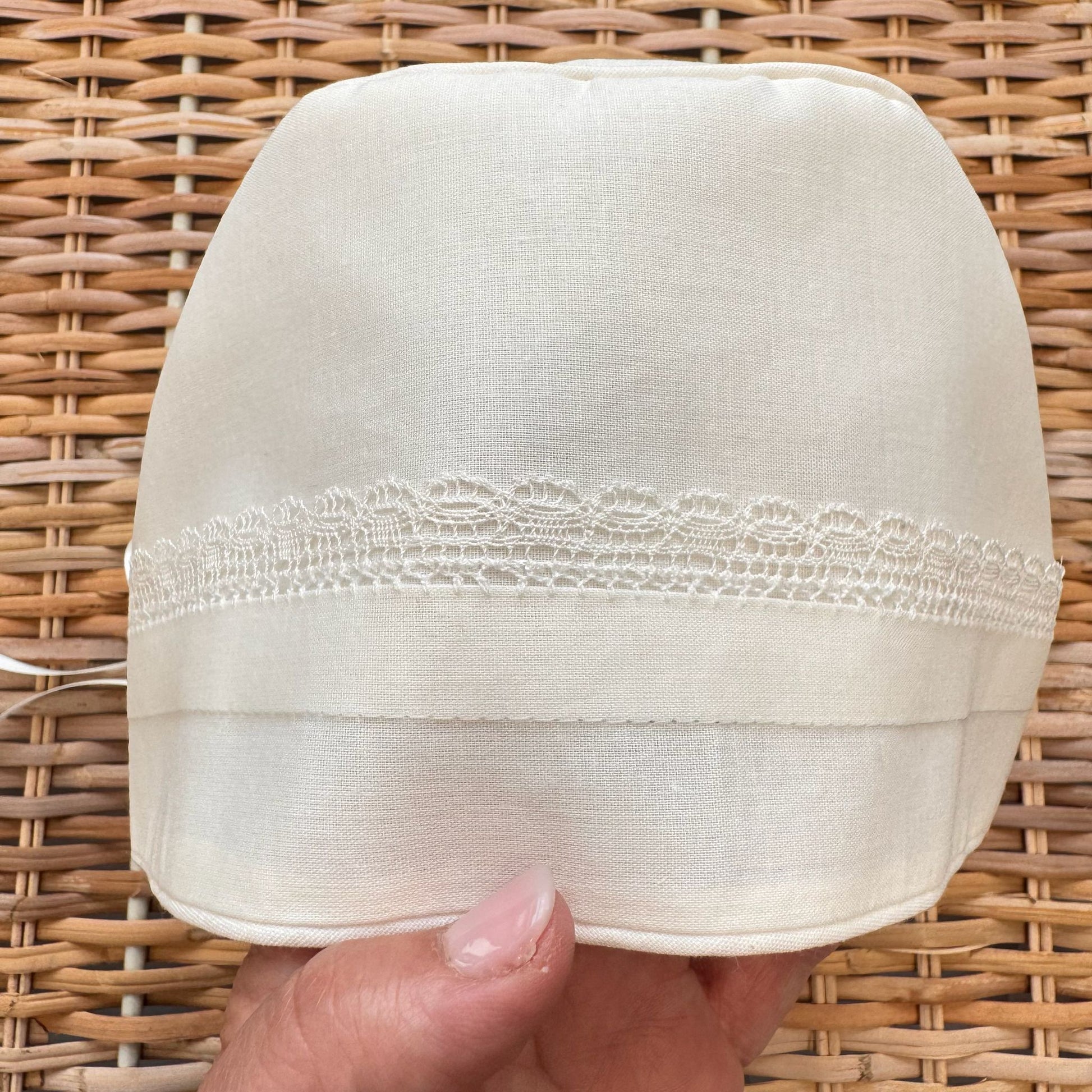 Cuffietta battesimale unisex bianca con ricamo decorativo e laccetti in raso.